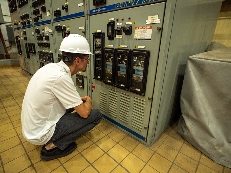 A Utility Services employee looking at a control panel.